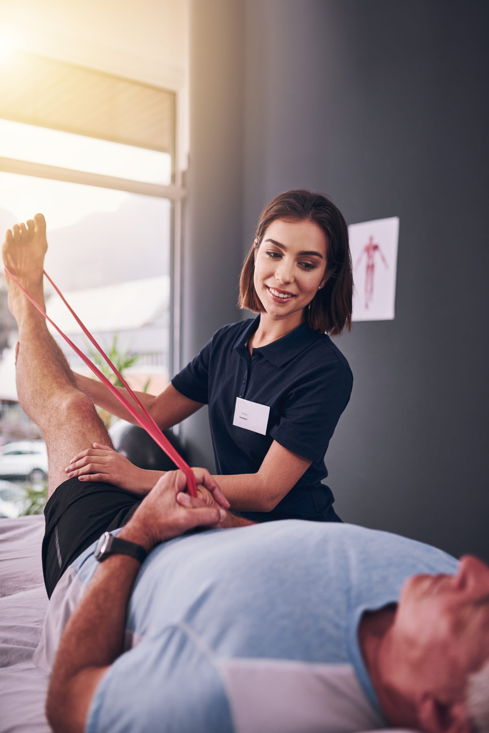 Physiotherapist, resistance band and woman with recovery, consultation for injury, expert or patient. Help, physical therapy and client with rehabilitation exercise or stretch leg for muscle strength.